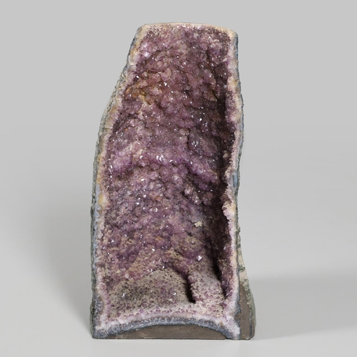 567 - LARGE AMETHYST GEODE. A large Amethyst Geode with a curved shaped back, 67cms high.