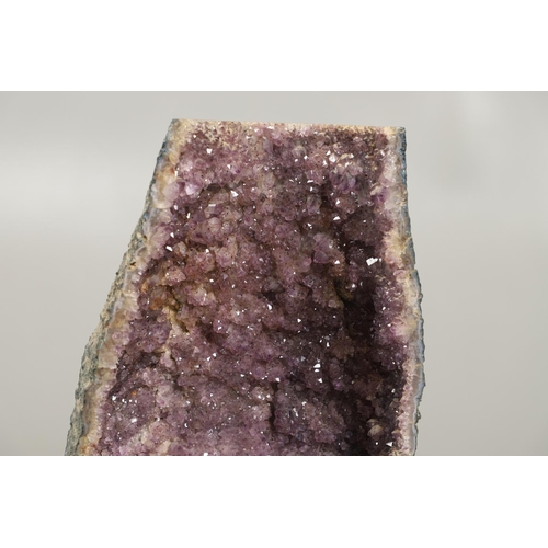 567 - LARGE AMETHYST GEODE. A large Amethyst Geode with a curved shaped back, 67cms high.