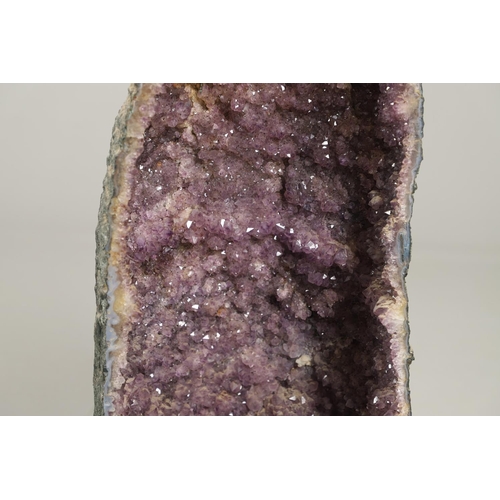 567 - LARGE AMETHYST GEODE. A large Amethyst Geode with a curved shaped back, 67cms high.