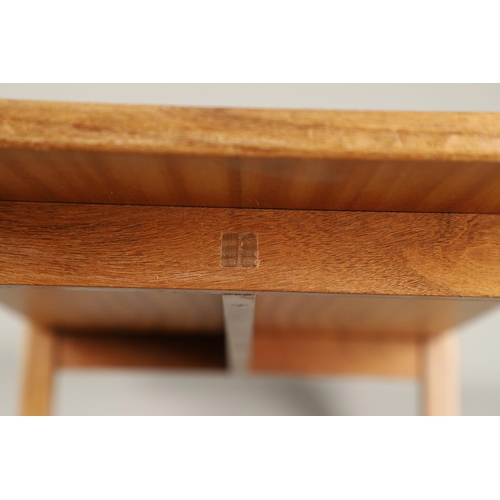 584 - COTSWOLD SCHOOL WALNUT COFFEE TABLE. The walnut table with a rectangular shaped top, supported on le... 