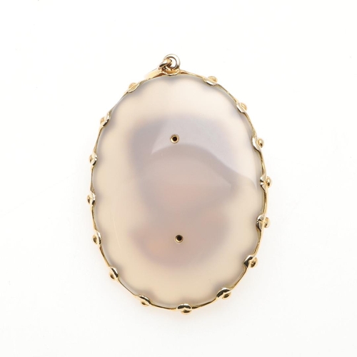 1009 - A CHALCEDONY AND GOLD PENDANT. the oval-shaped chalcedony pendant mounted with a gold carved head an... 