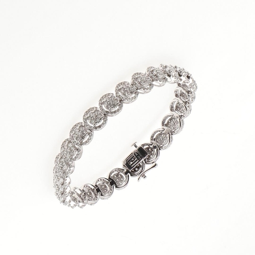 1015 - A DIAMOND BRACELET. formed with overlapping diamond clusters, in white gold, the diamonds weigh 5.00... 