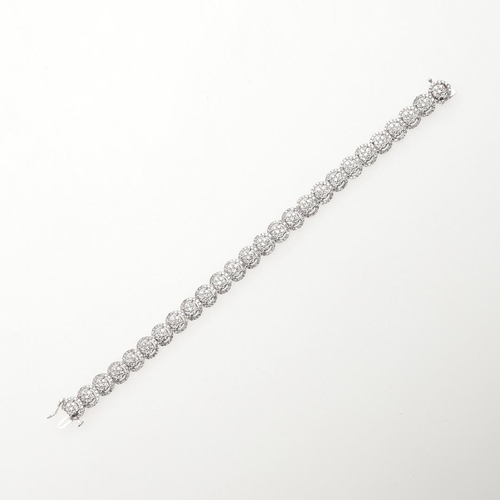 1015 - A DIAMOND BRACELET. formed with overlapping diamond clusters, in white gold, the diamonds weigh 5.00... 