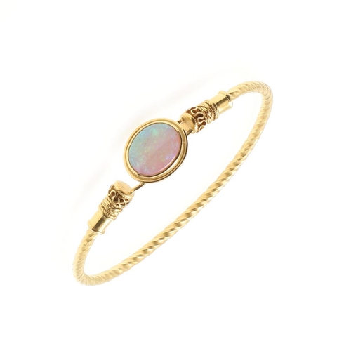 1019 - AN OPAL AND GOLD GOLD BANGLE. mounted with an oval solid white opal on a 21ct gold bangle, with orna... 