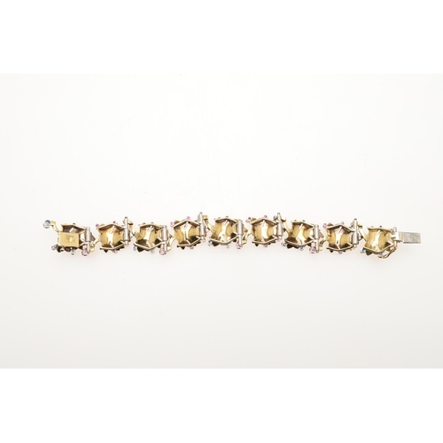 1041 - AN 18CT GOLD, RUBY AND SAPPHIRE BRACELET BY BIRKS OF CANADA. of maple leaf design, mounted with circ... 