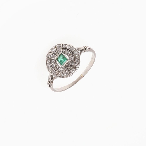 1055 - AN EMERALD AND DIAMOND CLUSTER RING. the rectangular-shaped emerald is set within a surround of grad... 