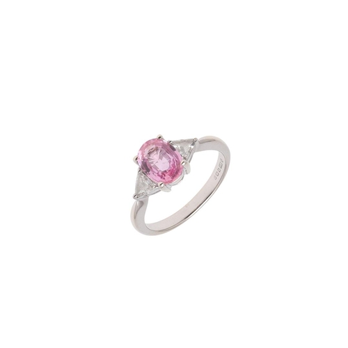 1062 - A PINK SAPPHIRE AND DIAMOND THREE STONE RING. the oval-shaped pink sapphire is set with two triangul... 