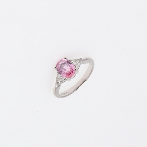 1062 - A PINK SAPPHIRE AND DIAMOND THREE STONE RING. the oval-shaped pink sapphire is set with two triangul... 