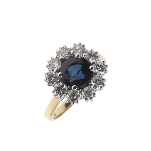 1066 - A SAPPHIRE AND DIAMOND CLUSTER RING. the circular-cut sapphire is set within a surround of brilliant... 