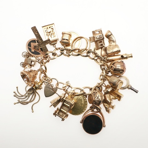 799 - A 9CT GOLD CURB LINK CHARM BRACELET. with padlock clasp and suspending many assorted 9ct gold charms... 