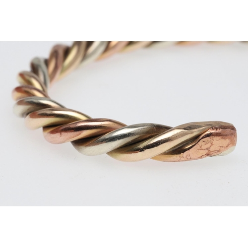 800 - A THREE COLOUR GOLD BANGLE. of twist form, internal measurement 6.0cm across, 37.4 grams.