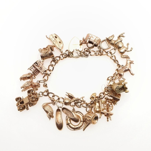 809 - A 9CT GOLD CHARM BRACELET. formed with oval-shaped links and suspending assorted 9ct gold charms, 71... 