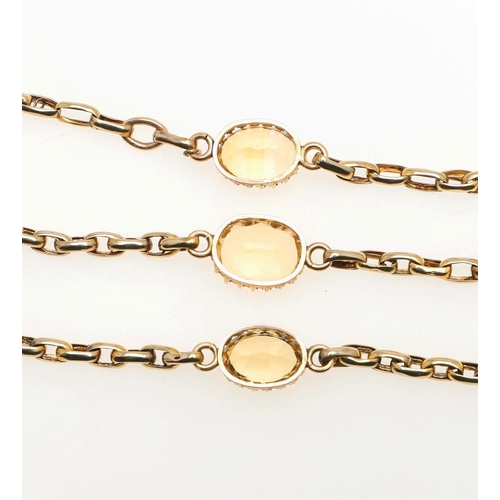 813 - A GOLD AND CITRINE LONG GUARD CHAIN. mounted with oval-shaped links and set with three claw set oval... 