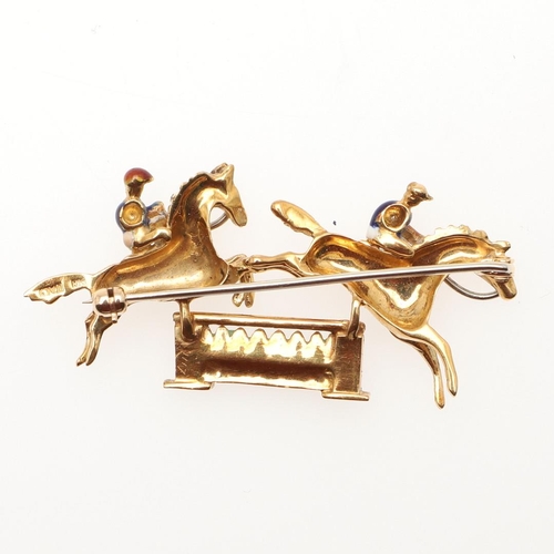 850 - AN 18CT GOLD AND ENAMEL HORSE AND JOCKEY BROOCH. depicting two jockeys jumping over a fence, with re... 