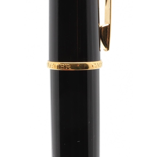 859 - A BLACK FOUNTAIN PEN BY CARTIER. with gold plated decoration, 18ct gold nip, in a red leather box by... 