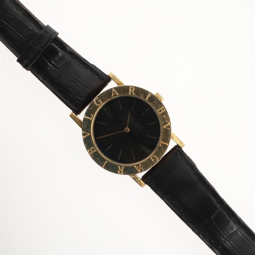 890 - AN 18CT GOLD WRISTWATCH BY BULGARI. the circular black dial with baton numerals and Arabic numerals ... 