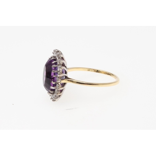 908 - AN AMETHYST AND DIAMOND CLUSTER RING. the oval-shaped amethyst is set within a surround of circular-... 