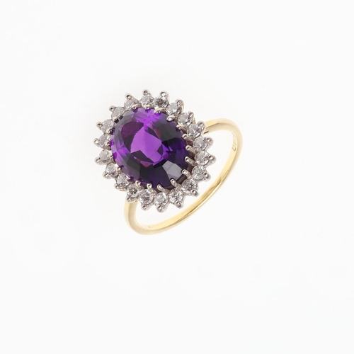 908 - AN AMETHYST AND DIAMOND CLUSTER RING. the oval-shaped amethyst is set within a surround of circular-... 