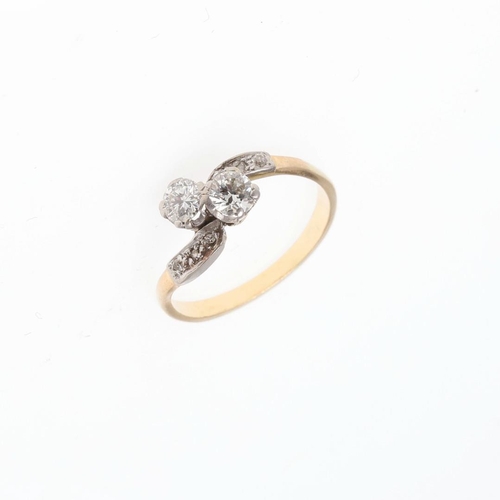 913 - A DIAMOND TWO STONE CROSS-OVER RING. set with two circular-cut diamonds, with further diamonds set t... 