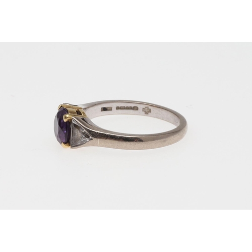 933 - A PURPLE SAPPHIRE AND DIAMOND THREE STONE RING. the circular-cut purple sapphire is set with a trian... 