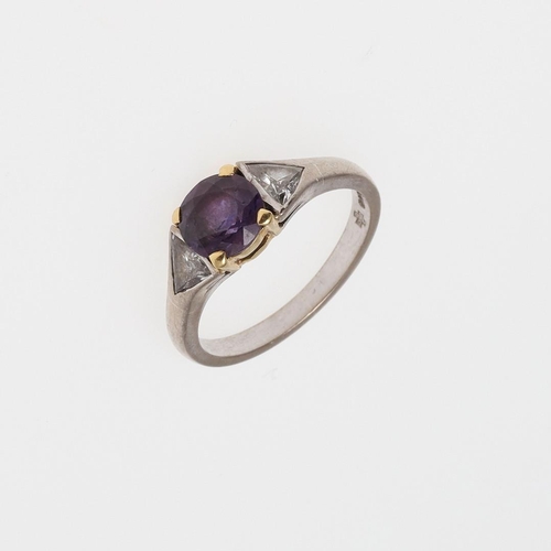 933 - A PURPLE SAPPHIRE AND DIAMOND THREE STONE RING. the circular-cut purple sapphire is set with a trian... 