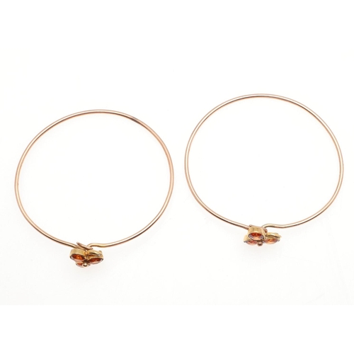 960 - A PAIR OF EDWARDIAN CITRINE AND DIAMOND SET GOLD WIRE BANGLES. each set with three oval-shaped citri... 