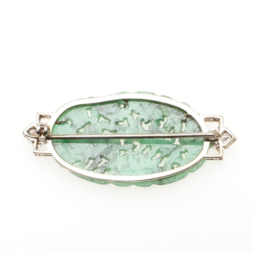 968 - AN ART DECO JADE AND DIAMOND BROOCH. mounted with an oval section of foliate carved and pierced jade... 