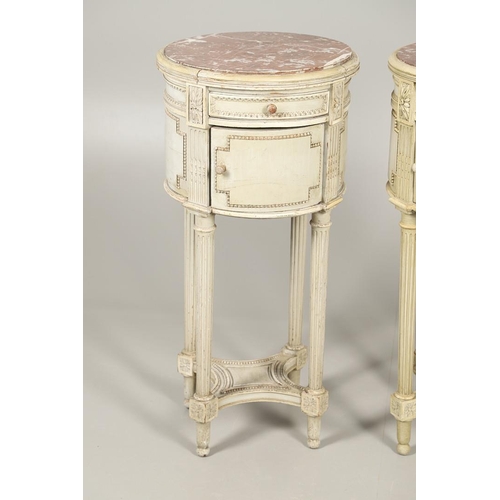 495 - A PAIR OF FRENCH MARBLE TOP PAINTED POT CUPBOARDS. of cylindrical form with moulded Classical motif ... 