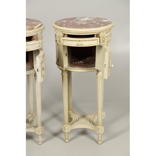 495 - A PAIR OF FRENCH MARBLE TOP PAINTED POT CUPBOARDS. of cylindrical form with moulded Classical motif ... 