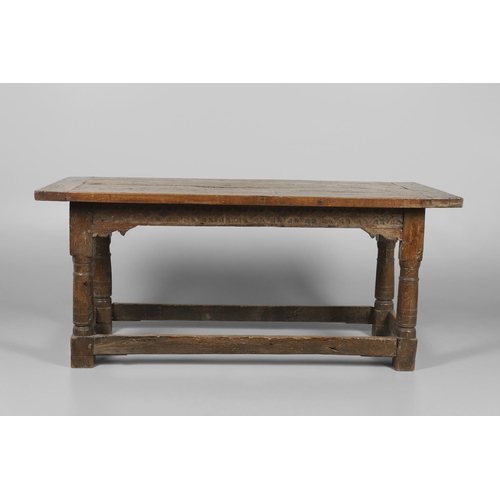 523 - A 17TH CENTURY AND LATER OAK REFECTORY TABLE. the four plank top over a carved frieze apron,  stretc... 