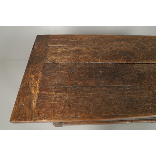 523 - A 17TH CENTURY AND LATER OAK REFECTORY TABLE. the four plank top over a carved frieze apron,  stretc... 