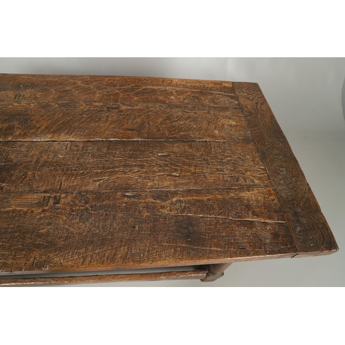 523 - A 17TH CENTURY AND LATER OAK REFECTORY TABLE. the four plank top over a carved frieze apron,  stretc... 