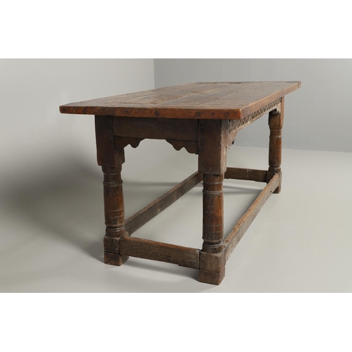 523 - A 17TH CENTURY AND LATER OAK REFECTORY TABLE. the four plank top over a carved frieze apron,  stretc... 