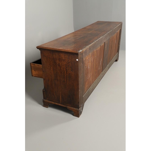 526 - A GEORGE III OAK DRESSER BASE. the double plank top over seven drawers and central shelved ogee pane... 