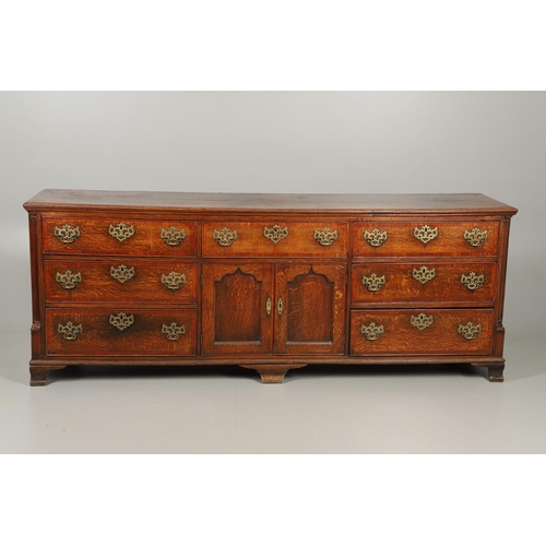 526 - A GEORGE III OAK DRESSER BASE. the double plank top over seven drawers and central shelved ogee pane... 