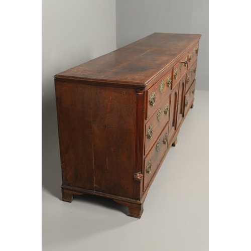 526 - A GEORGE III OAK DRESSER BASE. the double plank top over seven drawers and central shelved ogee pane... 