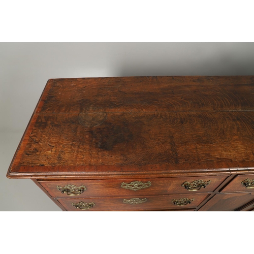 526 - A GEORGE III OAK DRESSER BASE. the double plank top over seven drawers and central shelved ogee pane... 