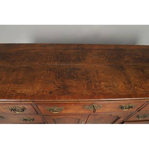 526 - A GEORGE III OAK DRESSER BASE. the double plank top over seven drawers and central shelved ogee pane... 