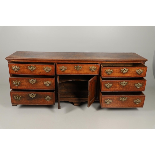 526 - A GEORGE III OAK DRESSER BASE. the double plank top over seven drawers and central shelved ogee pane... 