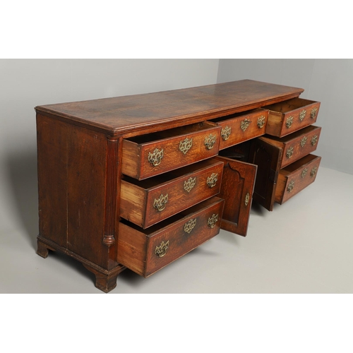 526 - A GEORGE III OAK DRESSER BASE. the double plank top over seven drawers and central shelved ogee pane... 