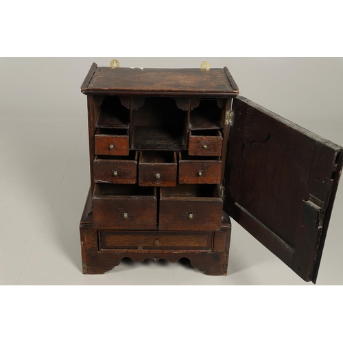 532 - A 17TH CENTURY OAK SPICE CUPBOARD. the panelled door revealing a pigeon hole interior and seven smal... 