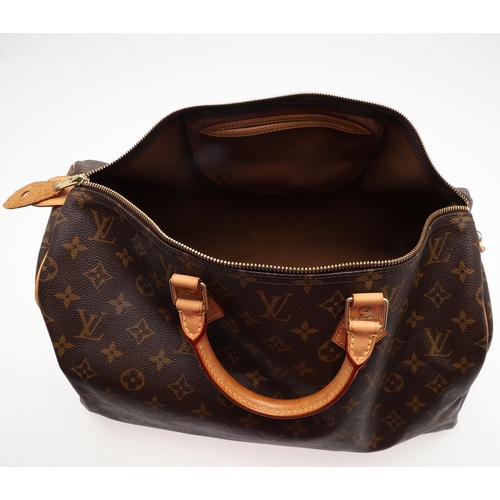 555 - LOUIS VUITTON 'SPEEDY' HANDBAG. A monogrammed and leather handbag with pouch to the interior, with a... 