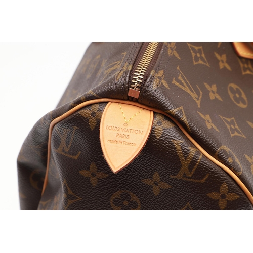 555 - LOUIS VUITTON 'SPEEDY' HANDBAG. A monogrammed and leather handbag with pouch to the interior, with a... 