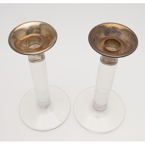 653 - PAIR OF CONTEMPORARY SILVER TOP & GLASS CANDLESTICKS. A pair of glass candlesticks with a circular f... 