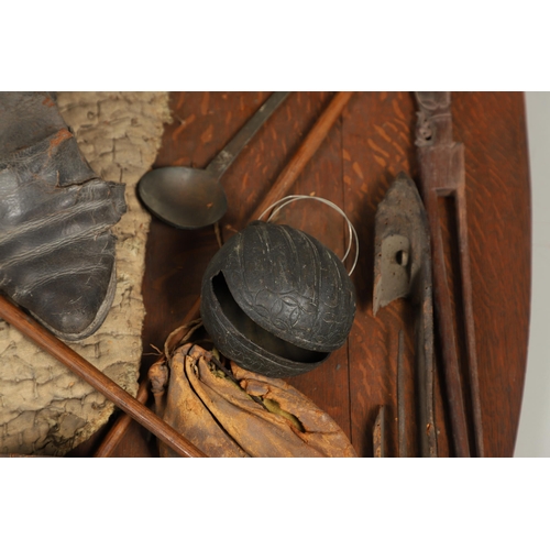 227 - AN UNUSUAL OAK SHIELD MOUNTED WITH MILITARY TROPHIES, CURIOSITIES AND OTHER ITEMS. An oak shield 89 ... 