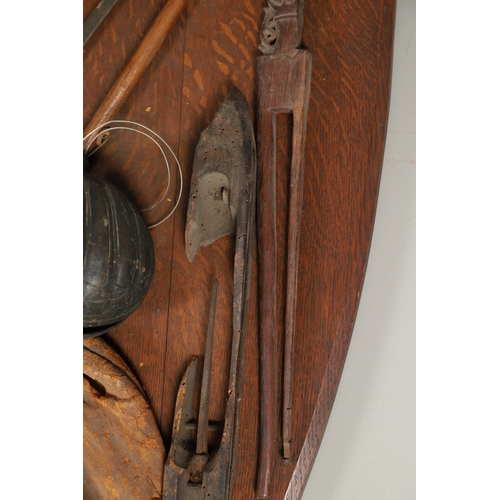 227 - AN UNUSUAL OAK SHIELD MOUNTED WITH MILITARY TROPHIES, CURIOSITIES AND OTHER ITEMS. An oak shield 89 ... 