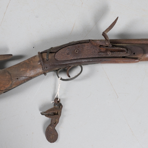 35 - A FLINTLOCK LONG GUN IN RELIC CONDITION AND SIMILAR SWORD. A flintlock gun with a 129 cm barrl, remn... 