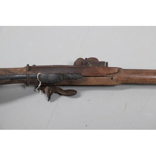 35 - A FLINTLOCK LONG GUN IN RELIC CONDITION AND SIMILAR SWORD. A flintlock gun with a 129 cm barrl, remn... 