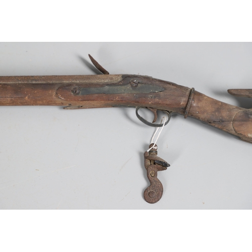 35 - A FLINTLOCK LONG GUN IN RELIC CONDITION AND SIMILAR SWORD. A flintlock gun with a 129 cm barrl, remn... 