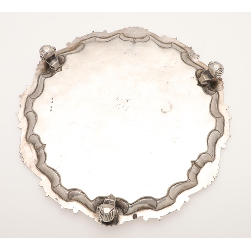 107 - AN 18TH CENTURY SILVER SALVER. of shaped circular outline, with a husk & scroll border and raised on... 